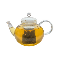 Teekanne aus Glas mit flüssigem Jasmintee und losen Grünteeblättern