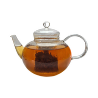 Teekanne aus Glas mit flüssigem Bergamotte Schwarztee und losen Schwarzteeblättern
